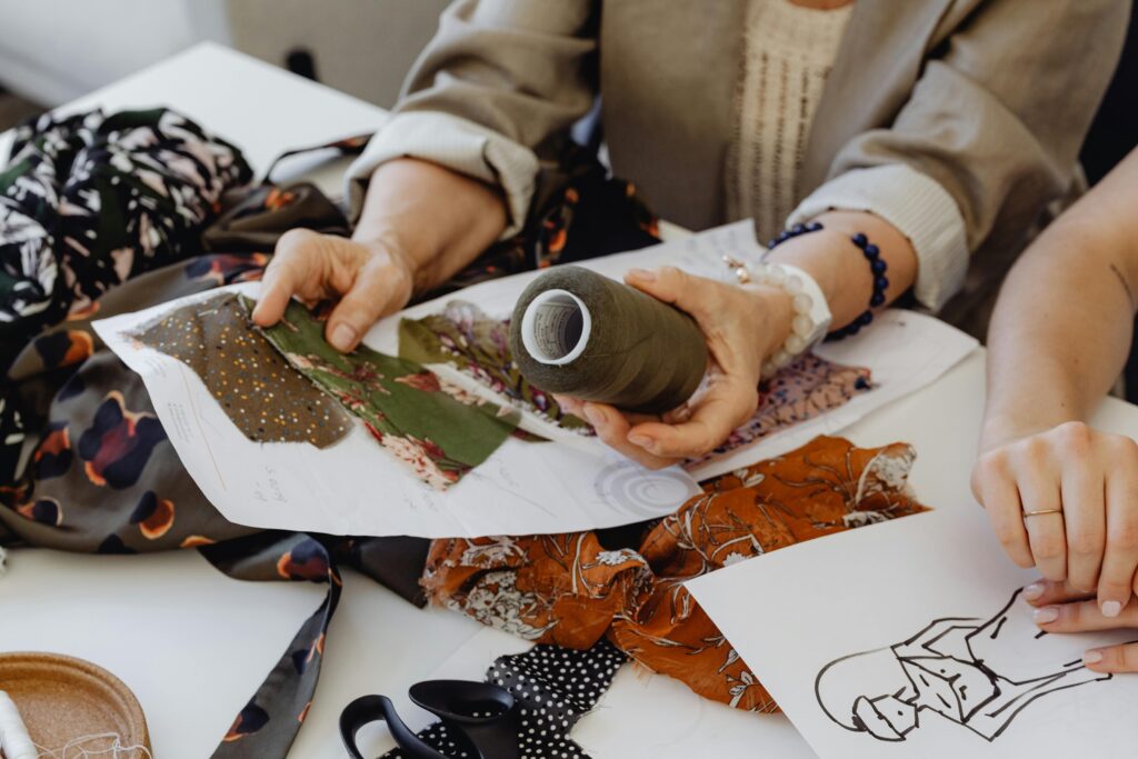 Elderly woman in a sewing workshop discussing designs with fabric swatches, promoting creativity.